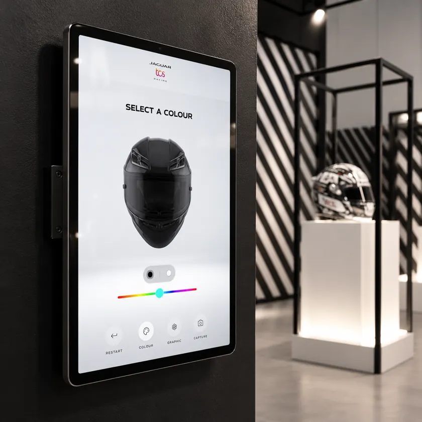 Fan holding a tablet showing their face wearing a custom-designed racing helmet in augmented reality