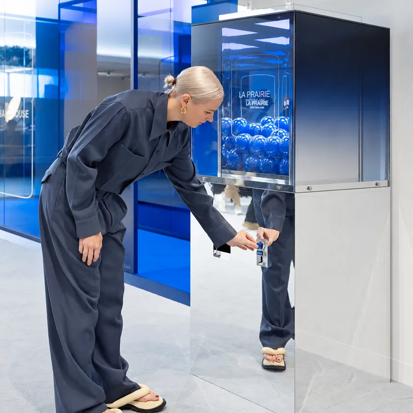 Glass-fronted vending machine whose mirrored, softly lit interior creates an infinity effect around product samples